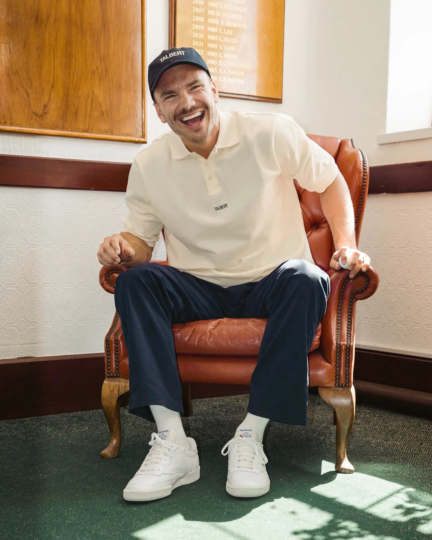 Model wearing Talbert Golf 001 Polo in cream in a golf clubhouse